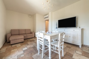 A living room with a sofa, dining table, chairs, a TV, and a cabinet.