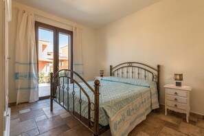 Une chambre à coucher avec un lit, une table de chevet, une fenêtre avec des rideaux et une vue sur les bâtiments à l’extérieur.