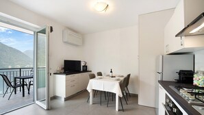 Une cuisine moderne avec un coin repas, un balcon offrant une vue agréable et un petit téléviseur.