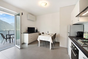 A modern kitchen with a dining area, a balcony with a view, and a small TV.