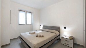 A bedroom with a bed, a bedside table with a lamp, and a window. - Appartamento 5 Il Tornante with Lake & Mountain Views, Wi-Fi, A/C & Balcony (Nesso)