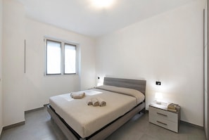 A bedroom with a bed, a bedside table with a lamp, and a window. - Appartamento 5 Il Tornante with Lake & Mountain Views, Wi-Fi, A/C & Balcony (Nesso)
