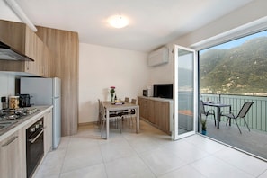 Une cuisine moderne avec un coin repas, un balcon offrant une vue sur les montagnes et une porte-fenêtre coulissante.