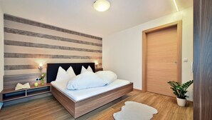 Un dormitorio moderno con una cama de madera, una mesita de noche, una lámpara de pared y una puerta.