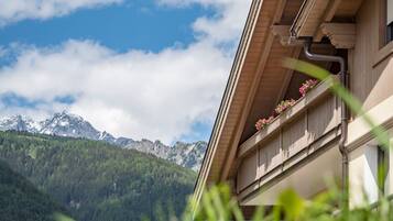 A mountain view with a building featuring a balcony with flowers.