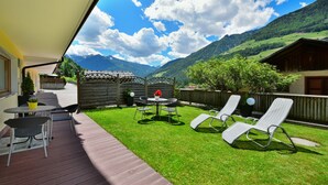 Un patio con mobiliario exterior, cerca de madera y vista a la montaña.