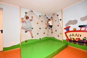 A climbing wall with colorful holds and a green padded floor. - Apartment "AlpenChalet Niederkofler Isabella" with Mountain View, Sauna & Garden (Ahrntal)