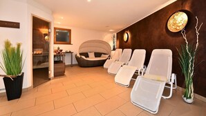 Een wellnessruimte met een receptiebalie, een rieten bank en meerdere ligbedden.