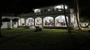 Un bâtiment doté de plusieurs arcades et d’un patio couvert, aménagé avec des espaces de détente en plein air et des hamacs.