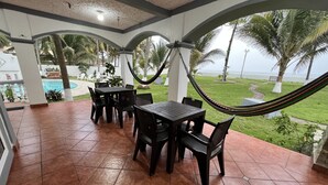 Un patio couvert avec une piscine, du mobilier d’extérieur et un hamac.