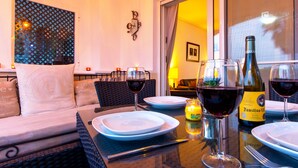 A dining area with a table set for two, a bottle of wine, and a candle on the table. - Townhouse overlooking golf course (La Torre Golf Resort)