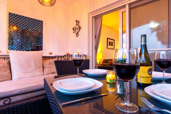 A dining area with a table set for two, a bottle of wine, and a candle on the table.