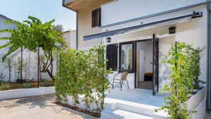 Une maison moderne à l’extérieur blanc, dotée d’un patio couvert avec des marches et d’une chaise.