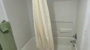 A bathroom with a shower curtain, a towel rack with a green towel, and a clear glass shower door. - Coratel Inn and Suites By Jasper Anthony (Anthony)