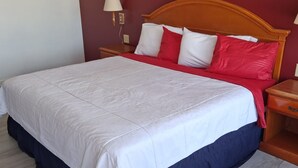 A bed with a white and red bedspread, wooden headboard, and bedside lamps. - Coratel Inn and Suites By Jasper Anthony (Anthony)