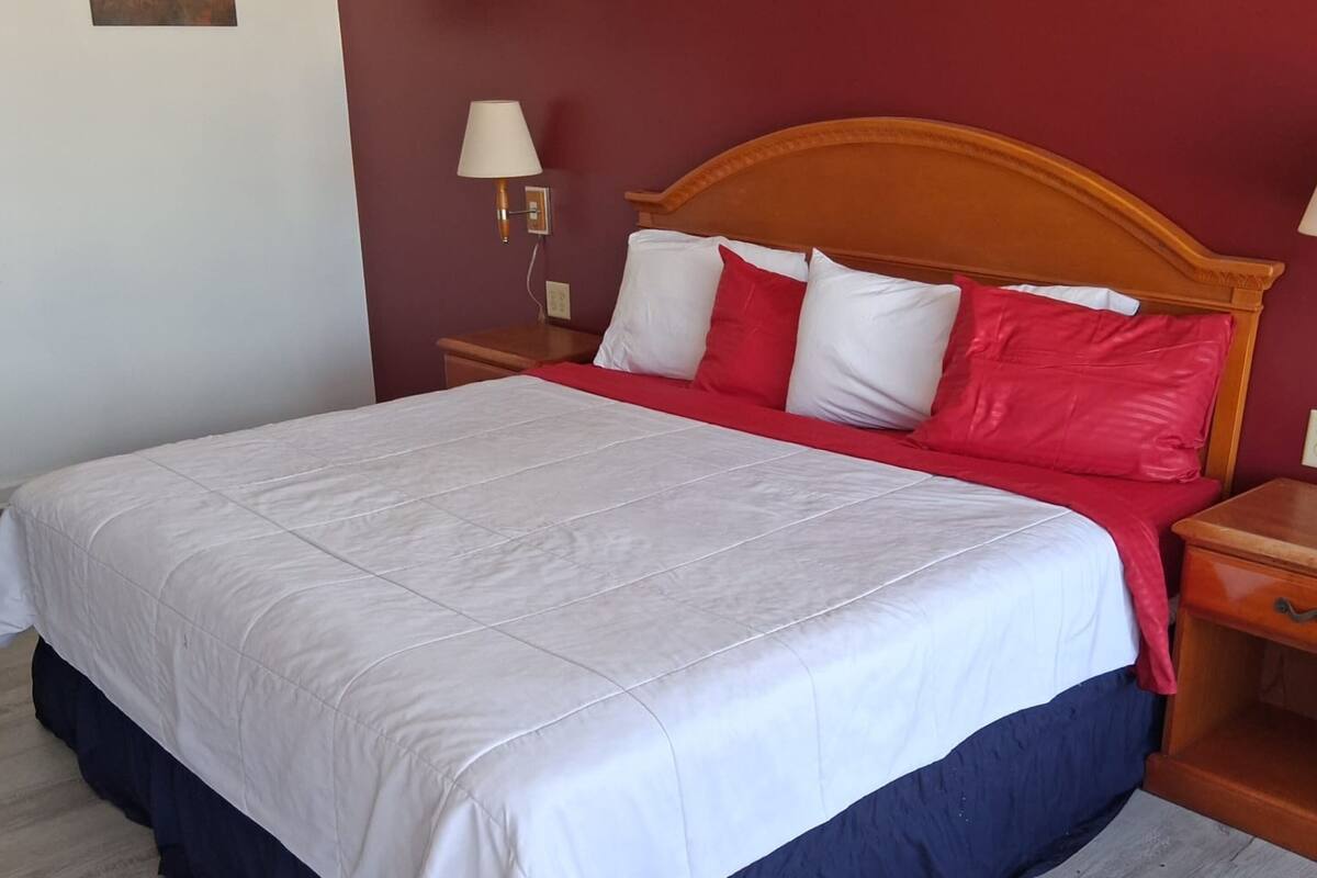 A bed with a white and red bedspread, wooden headboard, and bedside lamps.
