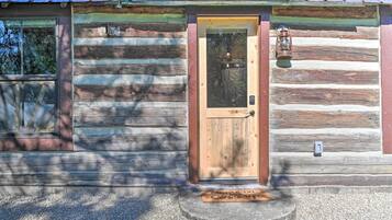 A log cabin with a wooden door, a window, and a lantern on the porch.