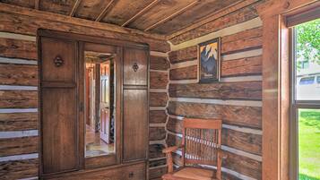 A log cabin interior with a wooden cabinet, a chair, and a framed picture on the wall.