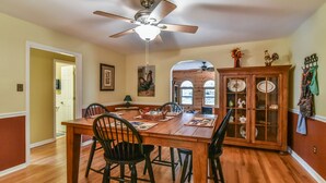A dining room with a wooden table, black chairs, a ceiling fan, and a glass-fronted cabinet with dishes. - Creekside Cottage Star 5 Vacations (Black Mountain)