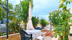 Ein Terrassenbereich im Freien mit Tisch und Stühlen, umgeben von Pflanzen und einer Steinmauer.