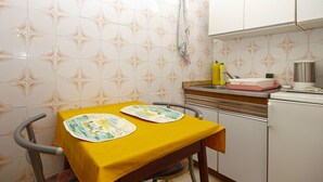 Eine kleine Küche mit einem gelben Tisch, zwei Stühlen und einem Spülbecken.