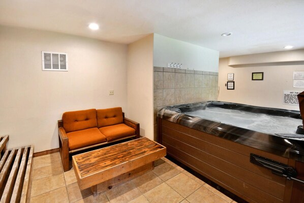 Un cuarto de spa con un banco de madera, un jacuzzi y un sofá.