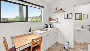 Eine moderne Küche mit Holztisch, weißen Schränken, einer Spüle und einem Fenster mit Blick ins Grüne.