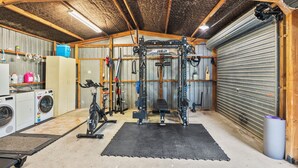Ein Fitnessraum mit einer Gewichthebevorrichtung, einem Ergometer und einer Waschmaschine.