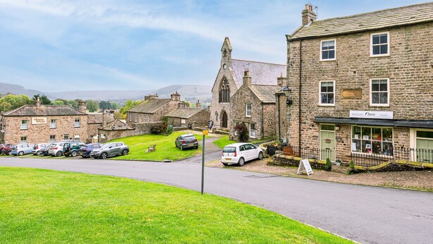 A quaint village street with stone buildings, a church, and parked cars. - Beautiful, 2 bedroom, first floor apartment, at the heart of a busting Dales Village. (Richmond)