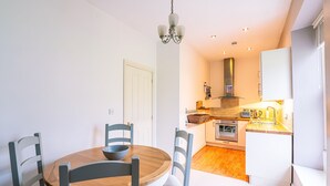 A modern kitchen with white cabinets, a wooden dining table, and a chandelier. - Beautiful, 2 bedroom, first floor apartment, at the heart of a busting Dales Village. (Richmond)