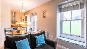 A modern kitchen with a dining area, a large window with a view, and a cozy seating area with a sofa and cushions. - Beautiful, 2 bedroom, first floor apartment, at the heart of a busting Dales Village. (Richmond)