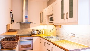 A kitchen with white cabinets, a stainless steel range hood, a microwave, and a sink. - Beautiful, 2 bedroom, first floor apartment, at the heart of a busting Dales Village. (Richmond)