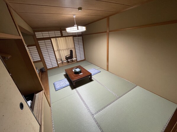 A traditional Japanese room with tatami flooring, a low wooden table, a ceiling light, and sliding doors. - Hotel Isodokei (Shirahama)