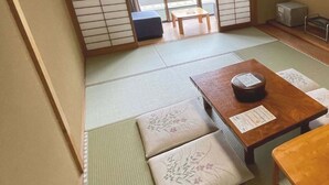 A tatami mat room with a low table and cushions. - Hotel Isodokei (Shirahama)