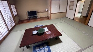 A traditional Japanese room with tatami flooring, a low table with a green tray, a television on a stand, and sliding doors. - Hotel Isodokei (Shirahama)