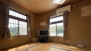 A room with tatami flooring, a television, and two windows with curtains. - Hotel Isodokei (Shirahama)