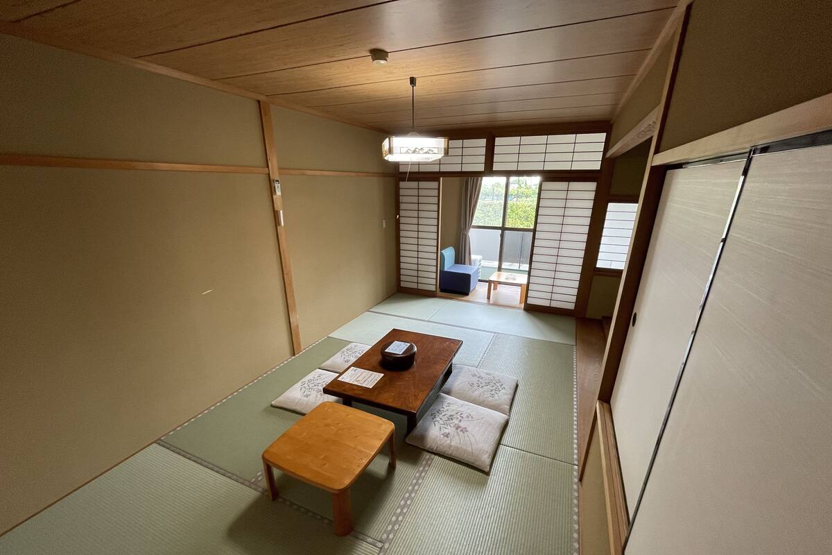 Une pièce de style japonais traditionnel, avec un sol recouvert de tatamis, une petite table basse en bois et un petit tabouret.