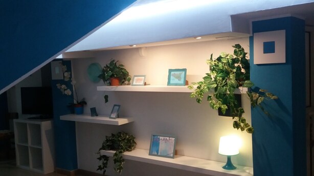 A staircase leading to a loft area with a blue accent wall, shelves with plants, and a lit lamp. - Laura's house 50 meters from the sea (giardini naxos)
