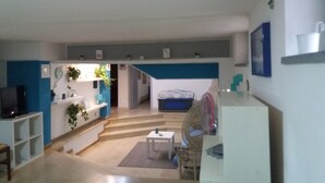 A living room with a television, a dining area with a table and chairs, and a kitchen area with a refrigerator and microwave. - Laura's house 50 meters from the sea (giardini naxos)