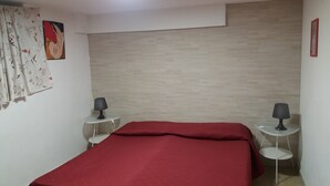 A bedroom with a bed, two bedside tables with lamps, a wall with a patterned curtain, and a light fixture. - Laura's house 50 meters from the sea (giardini naxos)