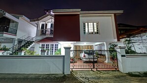 Une maison à deux étages avec une entrée fermée par un portail, un escalier et un balcon.