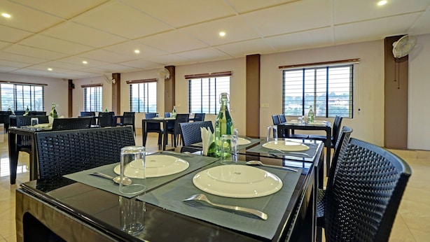 Un restaurant où les tables sont dressées pour le service, avec de la vaisselle en verre, des assiettes et des bouteilles bien disposées.