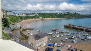 Une ville côtière dotée d’une plage de sable, d’un port de plaisance avec des bateaux et de bâtiments le long de la côte.