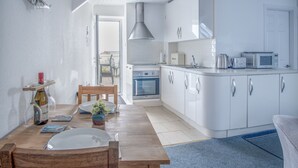 Une cuisine moderne avec des armoires blanches, un four encastré et un four à micro-ondes.