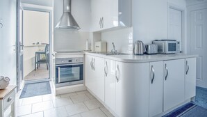 Une cuisine moderne avec des armoires blanches, des appareils en acier inoxydable et une grande fenêtre.