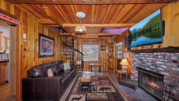 A wooden interior with a fireplace, leather sofa, and a staircase.