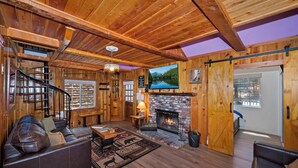 A wooden interior with a fireplace, leather sofa, and a TV mounted on the wall.