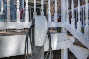 A white outdoor seating area with a Tesla charging station.