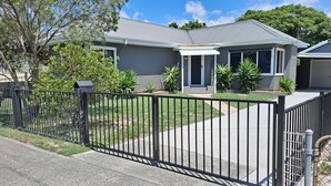 A two-story house with a grey exterior, a front porch, and a black metal fence. - 9 Breckenridge Street (Forster)