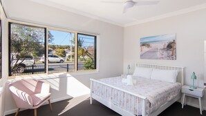 A bedroom with a large window, a bed, a chair, and a nightstand. - 9 Breckenridge Street (Forster)